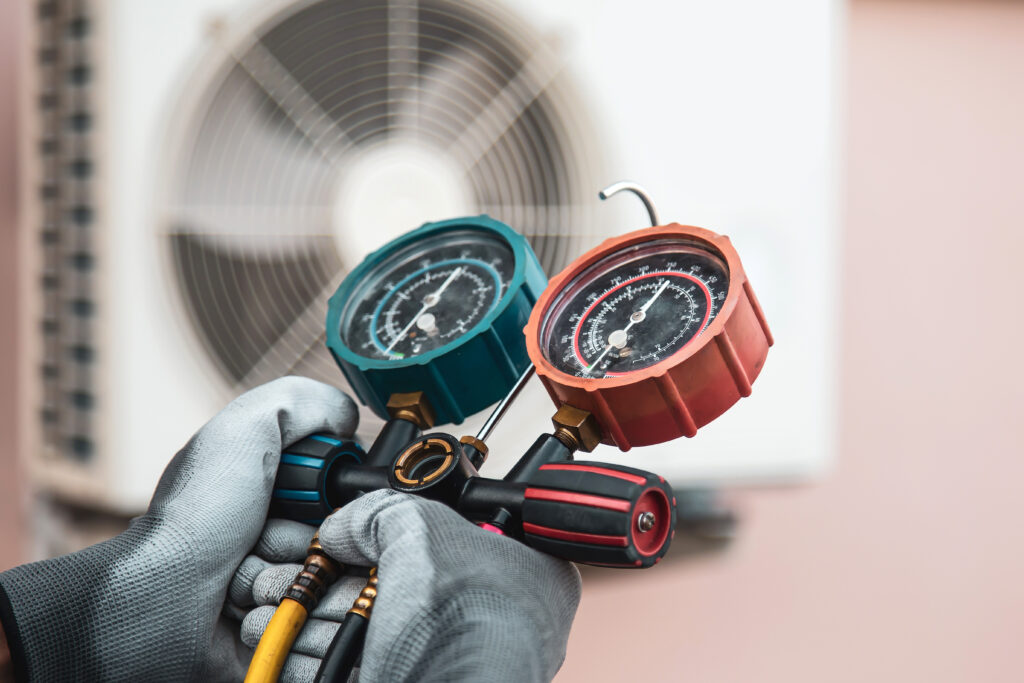 Mechanic air conditioner technician using manifold gauge checking refrigerant for filling home air conditioning after Tampa HVAC SEO services secured him leads