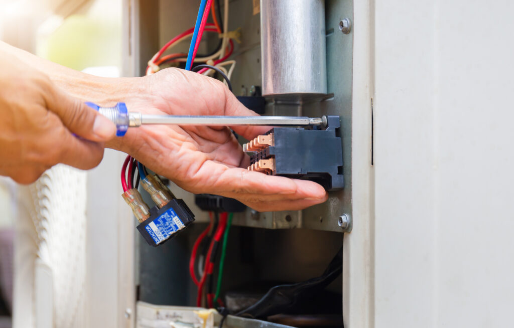 Close up of Air Conditioning Repair, repairman installing magnetic contactor and fixing air conditioning system after HVAC digital marketing earned them new jobs.