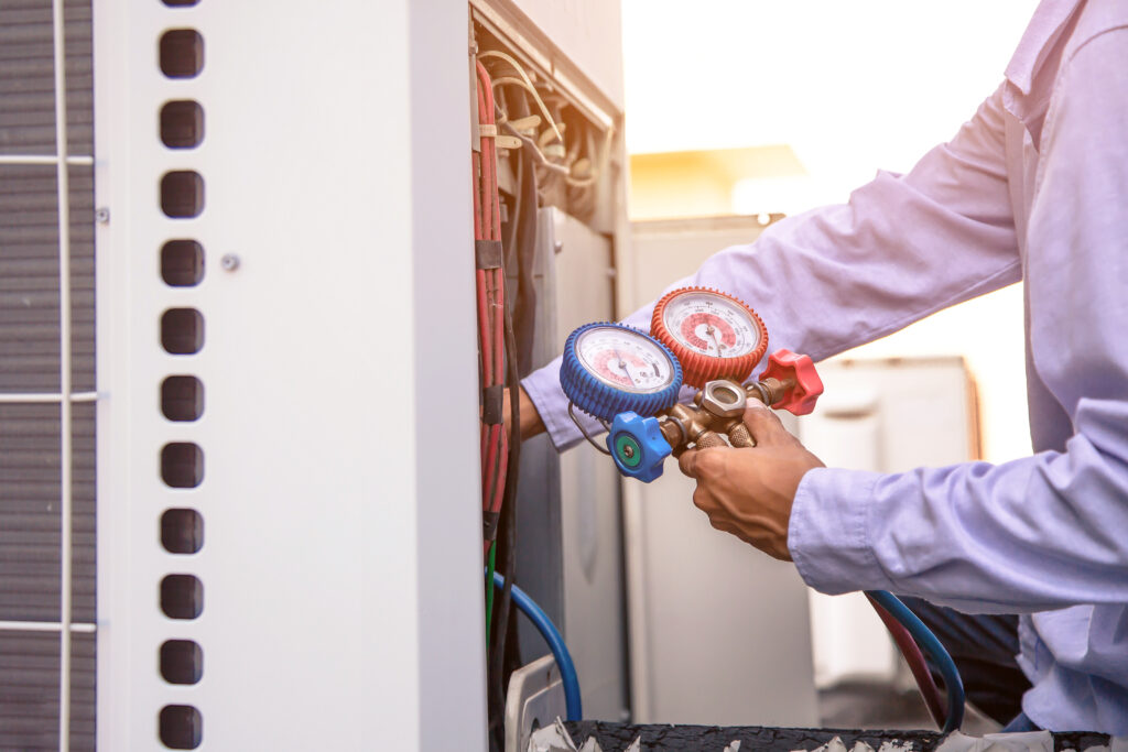 Technician using manifold gauge is measuring equipment for filling industrial factory air conditioners and checking maintenance outdoor air compressor unit after HVAC digital marketing filled their calendar.