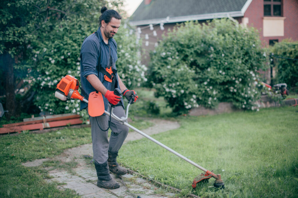 A man mows the grass with a hand mower in the garden after Tampa landscaping PPC services filled their schedule
