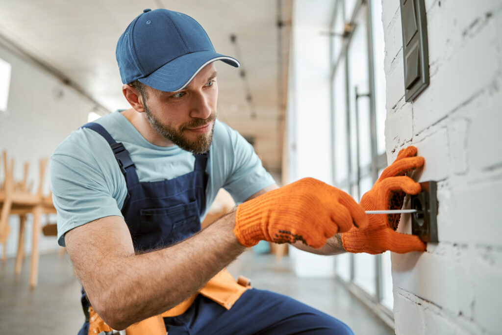 Electrician installing wall outlet in residential home kept busy by electrician SEO services in Tampa FL