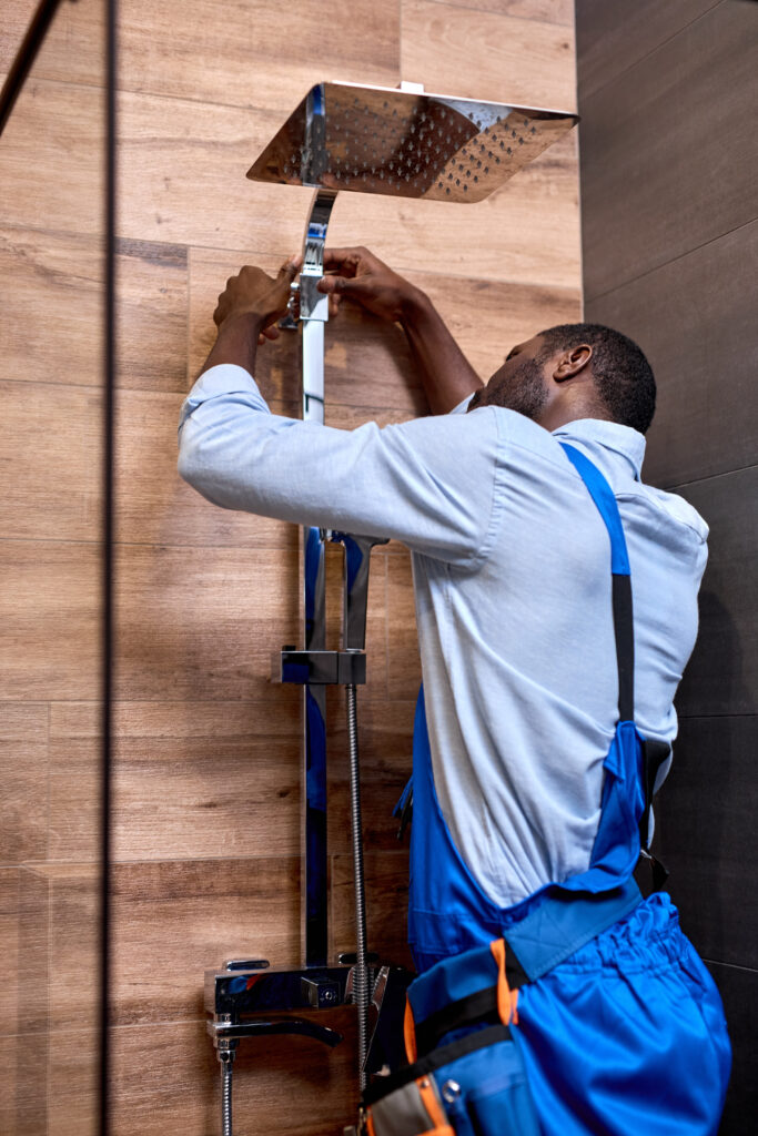 Plumber repairing fixing faucet in shower stall, after Tampa plumber PPC filled their schedule