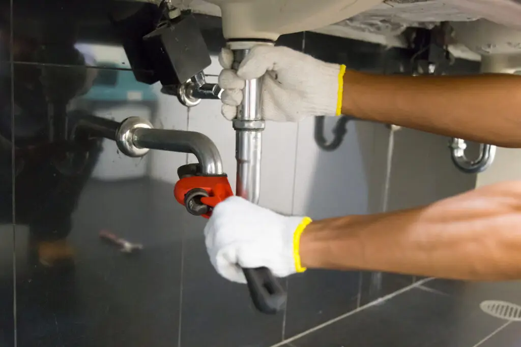 Plumber fixing white sink pipe with adjustable wrenchafter plumbing web design services created a site that filled their calendar with work.
