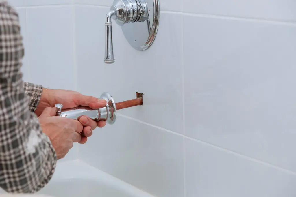Plumber installing water faucet shower with bathroom after plumbing web design services created a site that filled their calendar with work.