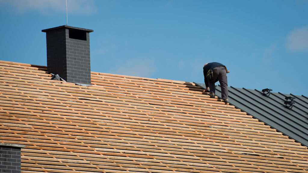 Building crew working on the roof sheeting after securing roofing leads.