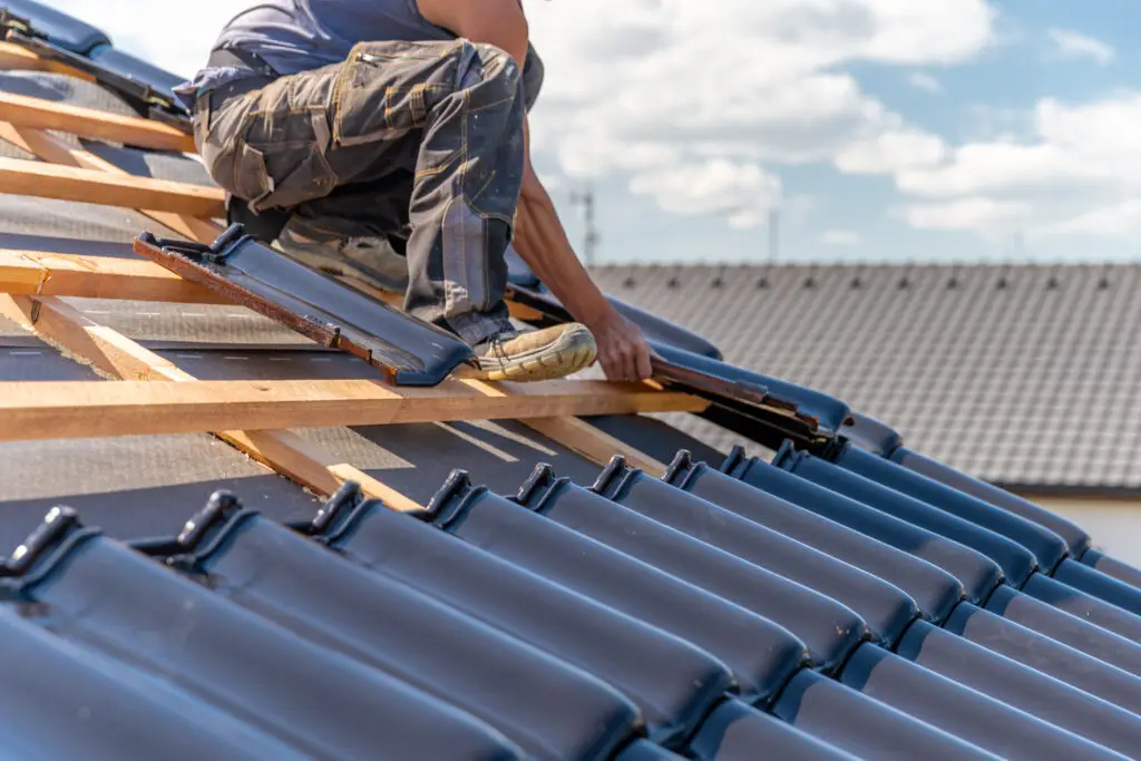 Roofer installs new tiles on wooden roof structure on a new building after roofing web design services created a site that filled their calendar with work.